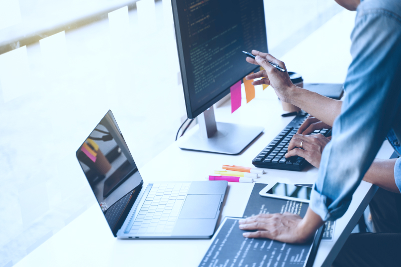 Person working at desk with computer, sticky notes, business environment